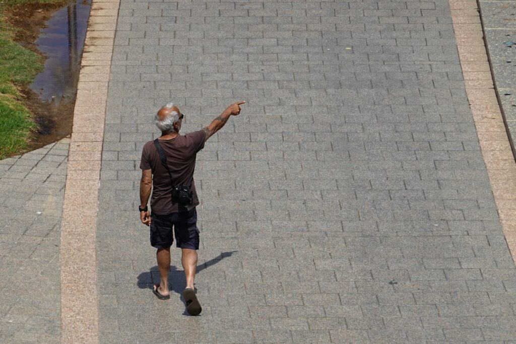Professional roofer in safety gear carefully inspects the shingles on a residential roof on a bright, sunny day, checking ...